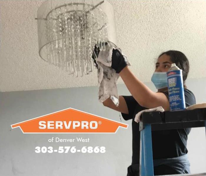 A SERVPRO of Denver West technician is cleaning a delicate cut glass chandelier.